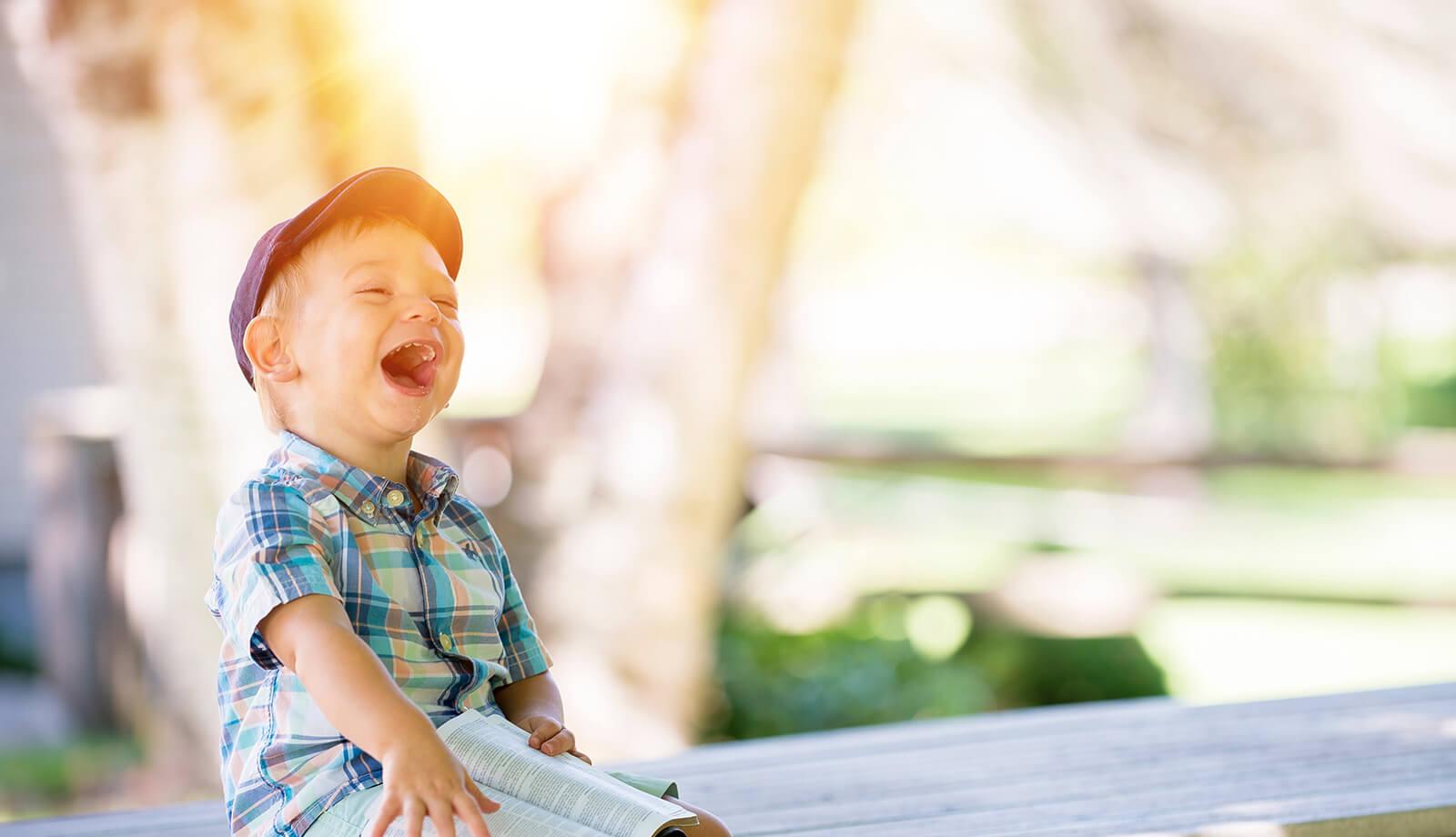 Lachendes Kind auf einer Bank (c) CC0 1.0 - Public Domain (von unsplash.com)